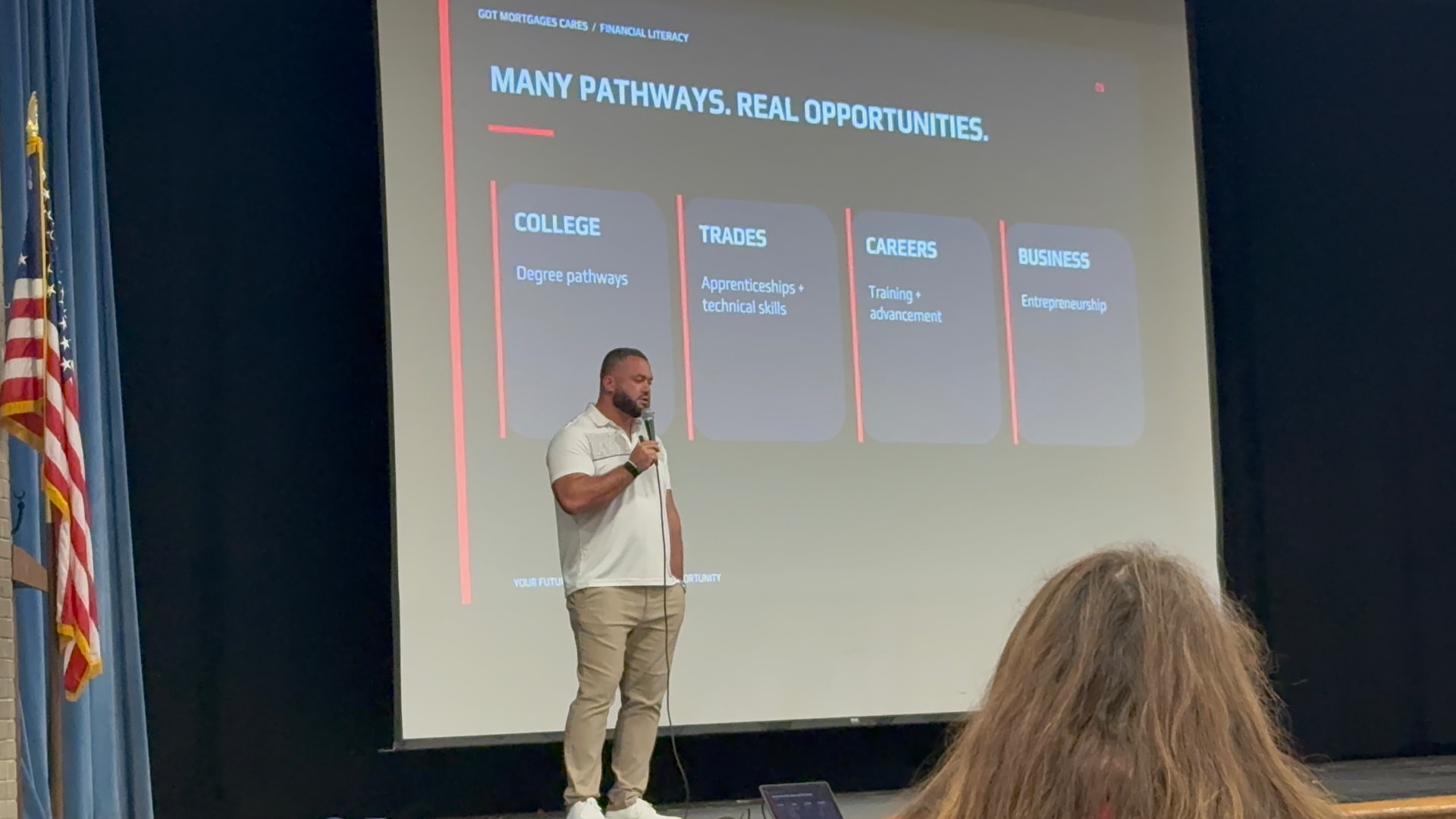 Presenter on stage at a Got Mortgages Cares financial literacy session with a slide titled Many Pathways. Real Opportunities